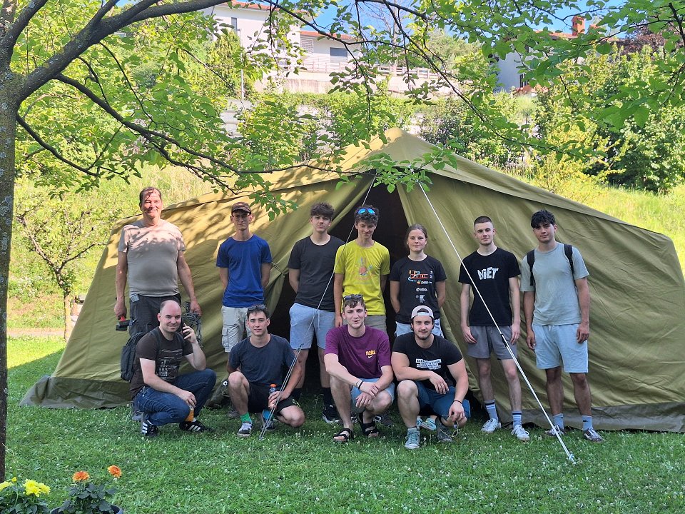 Skupina tabornikov se fotografira pred postavljenim šotorom